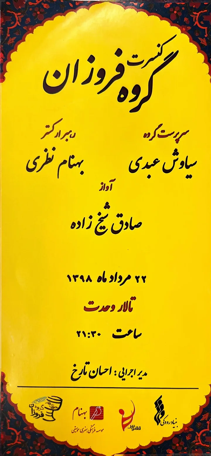 Photograph of a yellow Foroozan Ensemble concert poster with Persian calligraphy and a floral border.